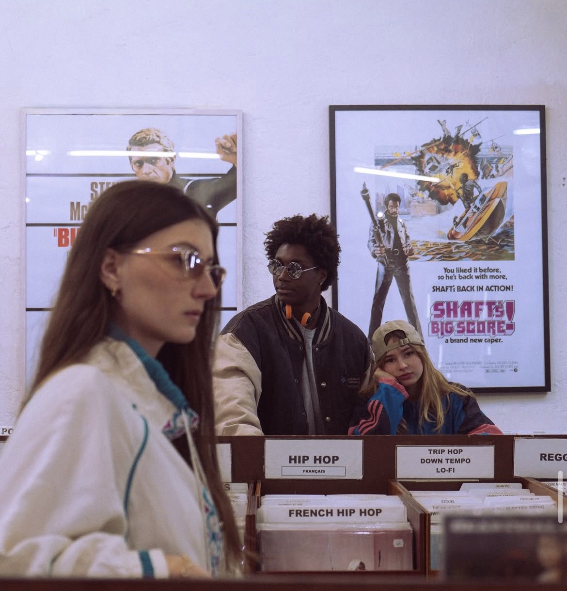 Des clients fouillent les bacs Hip-Hop sous les affiches de cinéma vintage.