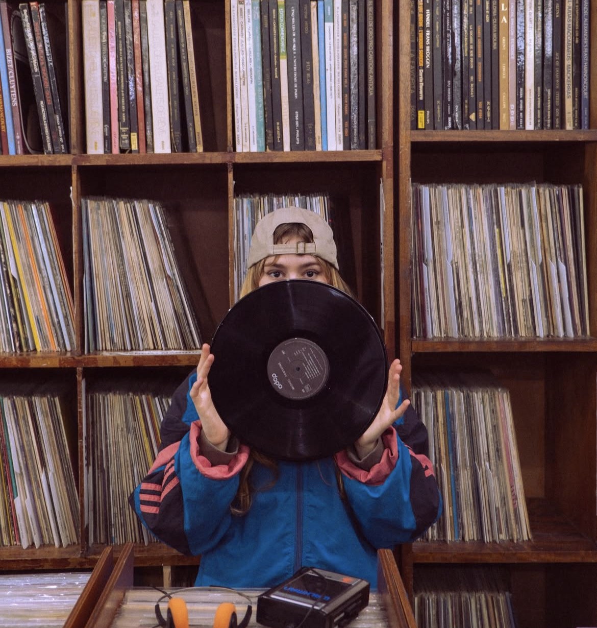 Une cliente présente un vinyle devant les bacs de disques.